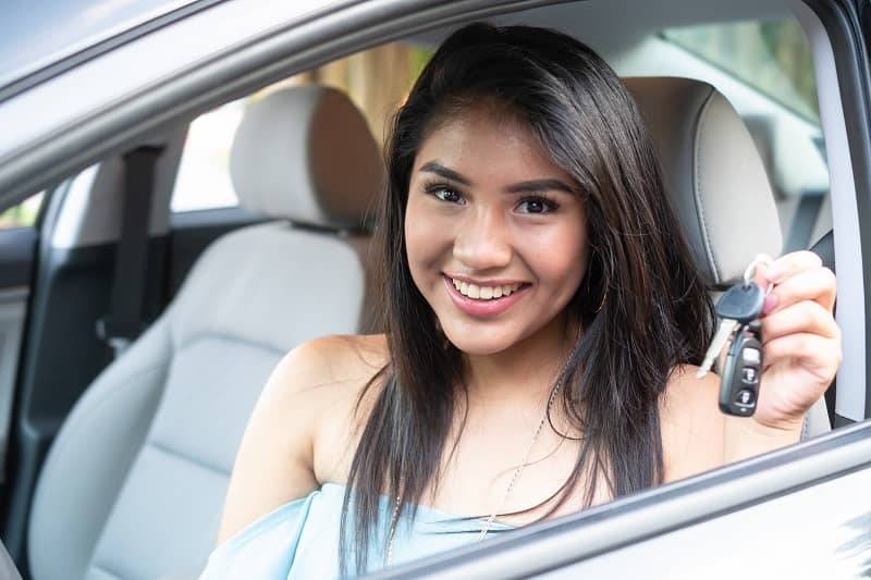 A teen girl holding keys to her new car