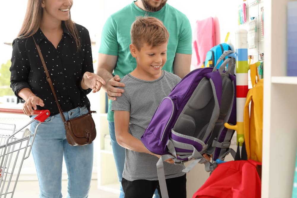 Parents helping their son pick out a purple backpack for school
