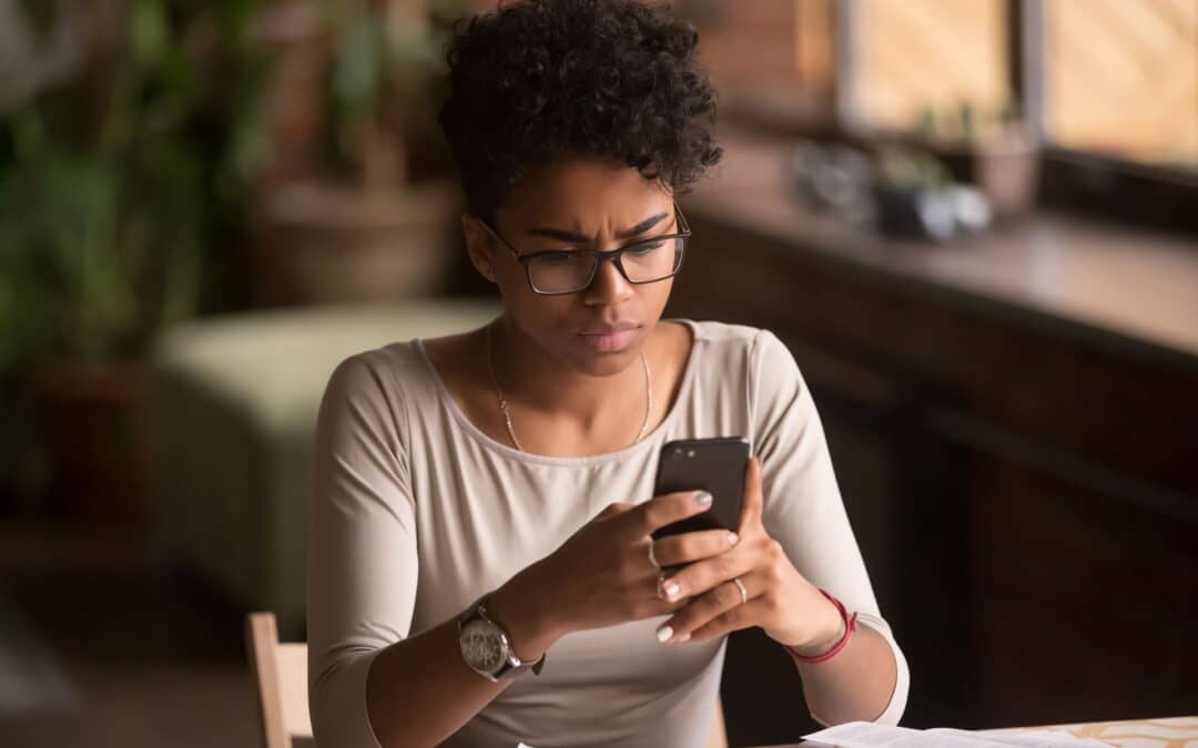 Woman looking confused at cell phone during a texting scam