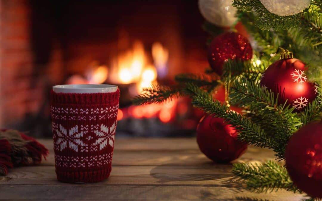 Cup of hot chocolate by the fireplace alongside a Christmas tree