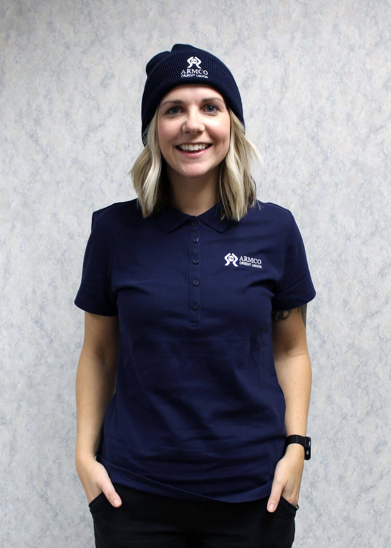 A girl wearing the navy Armco CU polo and beanie hat.